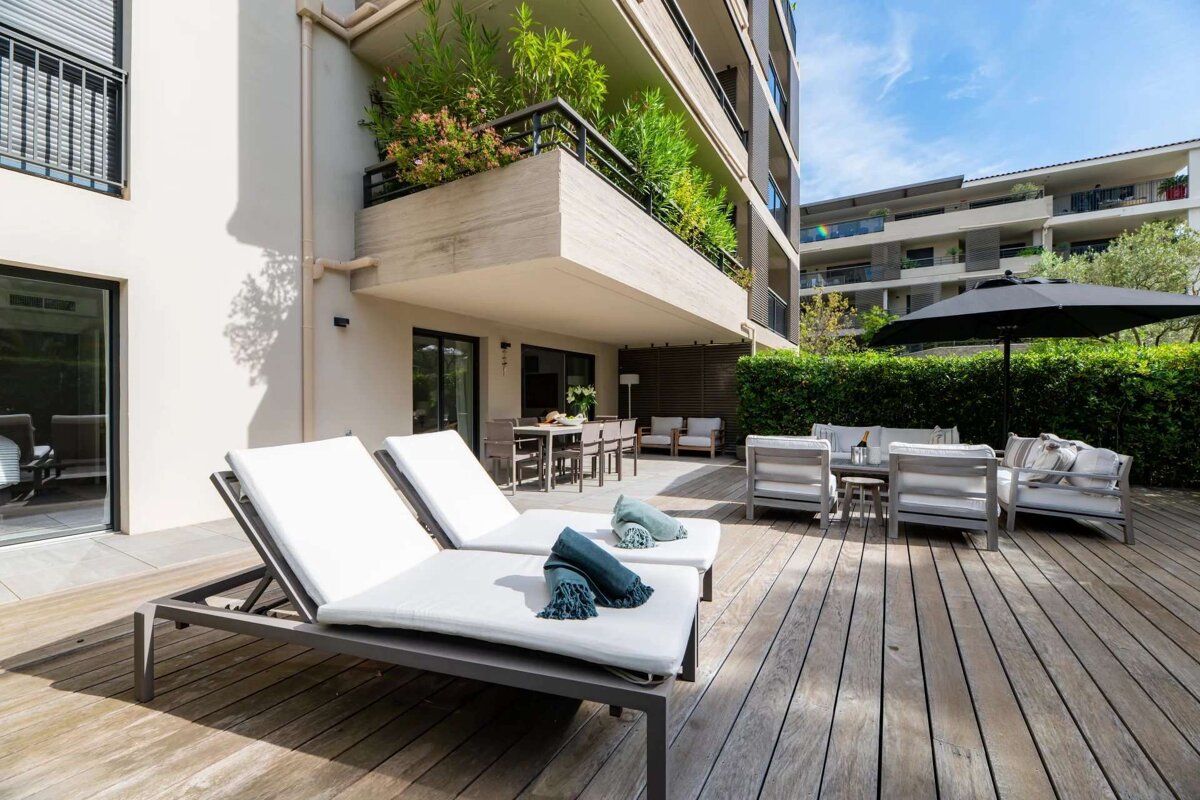 Two lounge chairs are on a wooden deck in front of a building