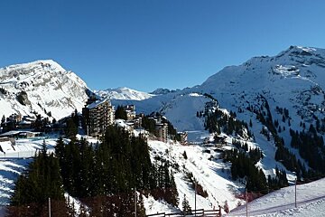 A snowy mountain with a ski resort in the background