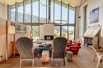 A living room with chairs and a fireplace with mountains in the background