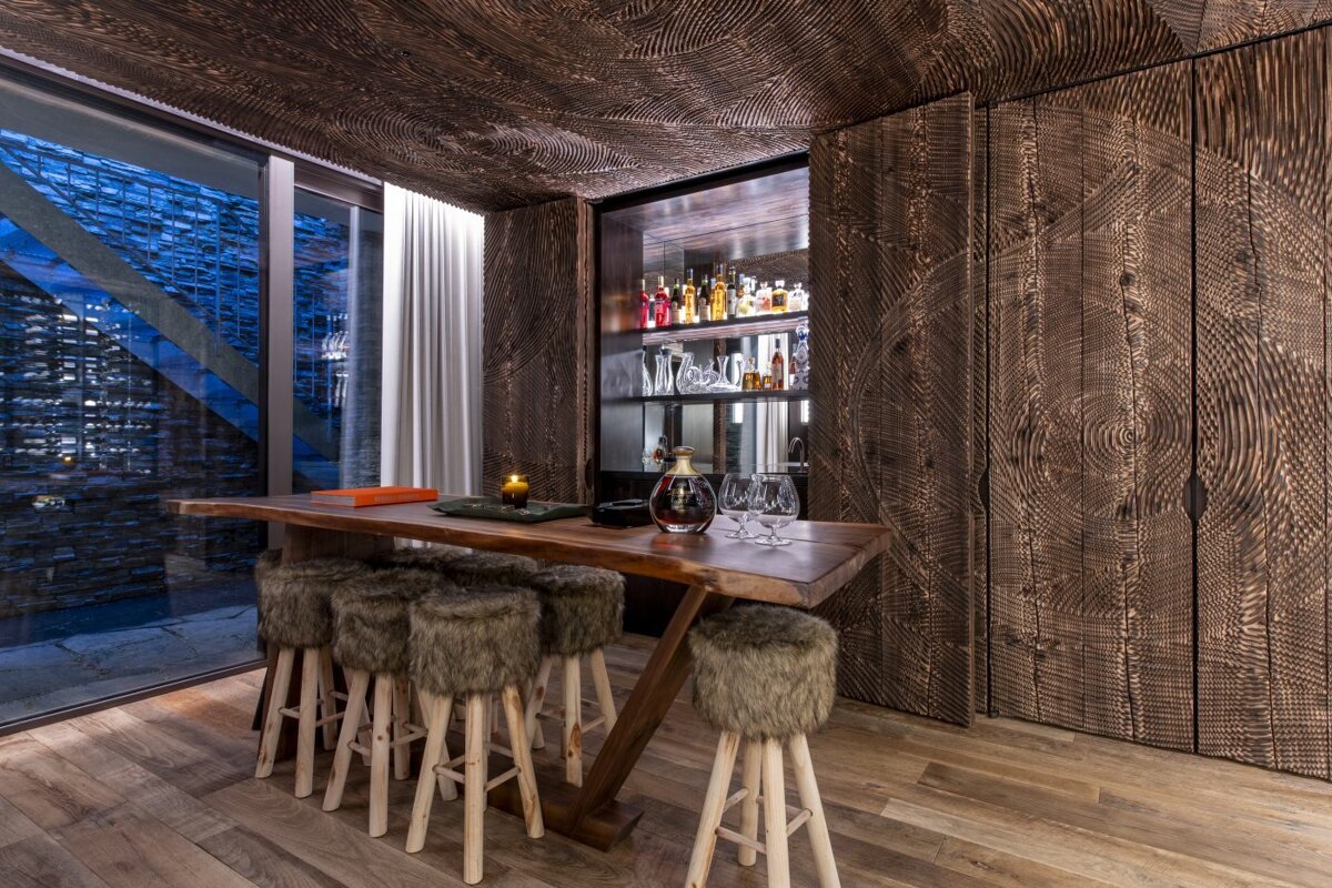 A room with a wooden table and furry stools