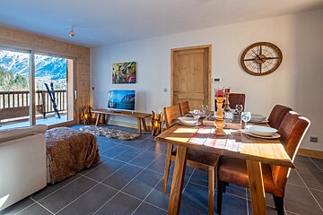 A living room with a table and chairs and a clock on the wall