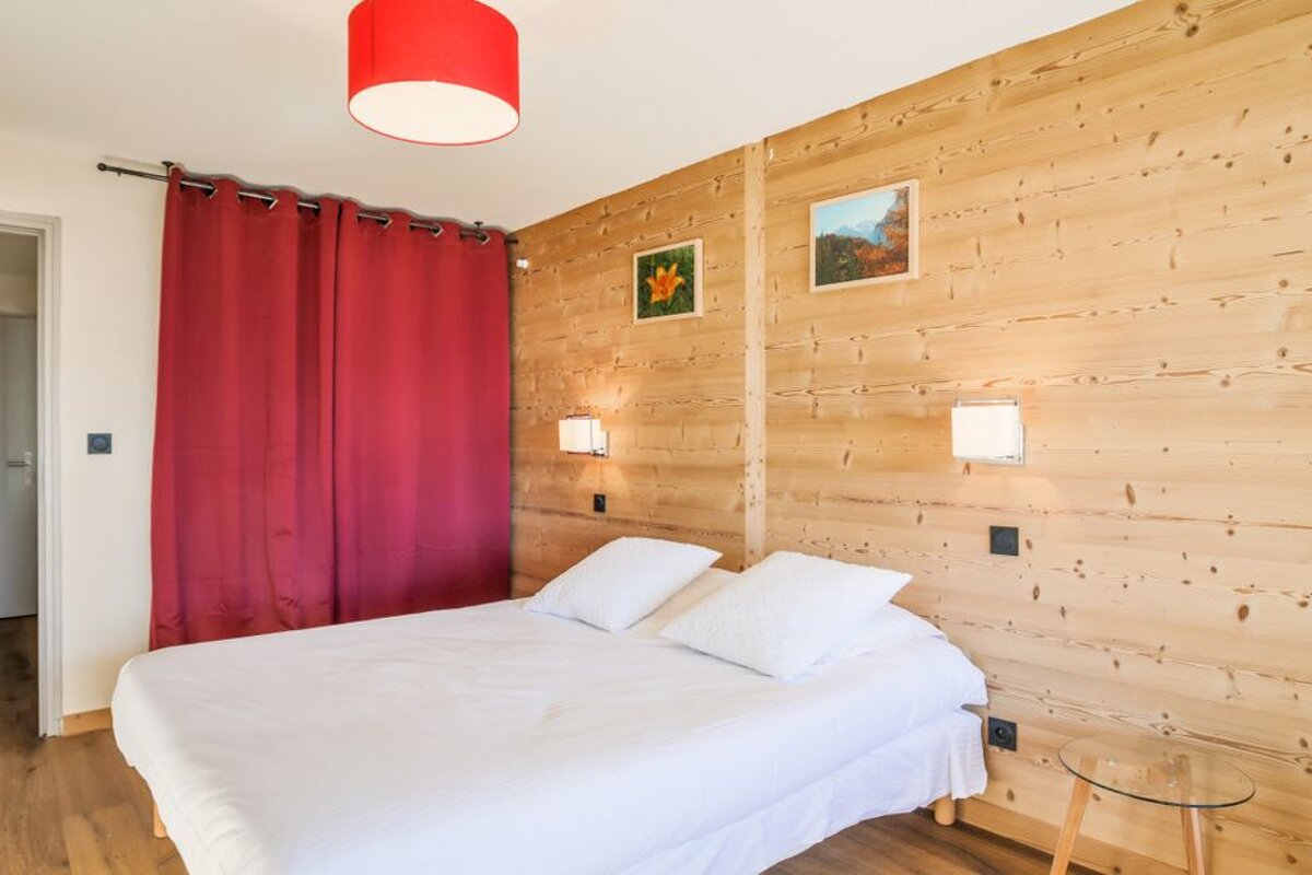 A bedroom with a bed and a red curtain