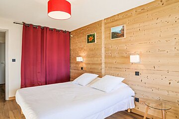 A bedroom with a bed and a red curtain