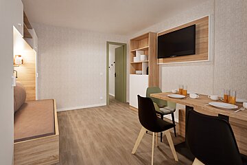 Modern, light-filled studio apartment with a dining area, wall-mounted TV, and a cozy sleeping nook. Features wooden flooring and light walls.