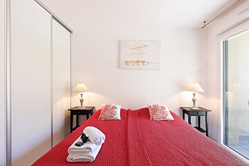 A bedroom with a red bed and two lamps