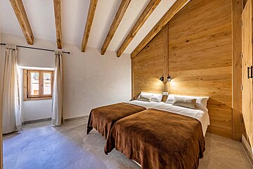 A bedroom with two beds and a wooden wall
