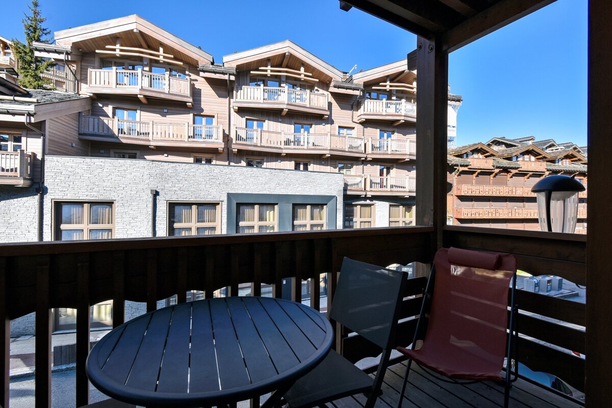 A balcony with a table and chairs with a building in the background