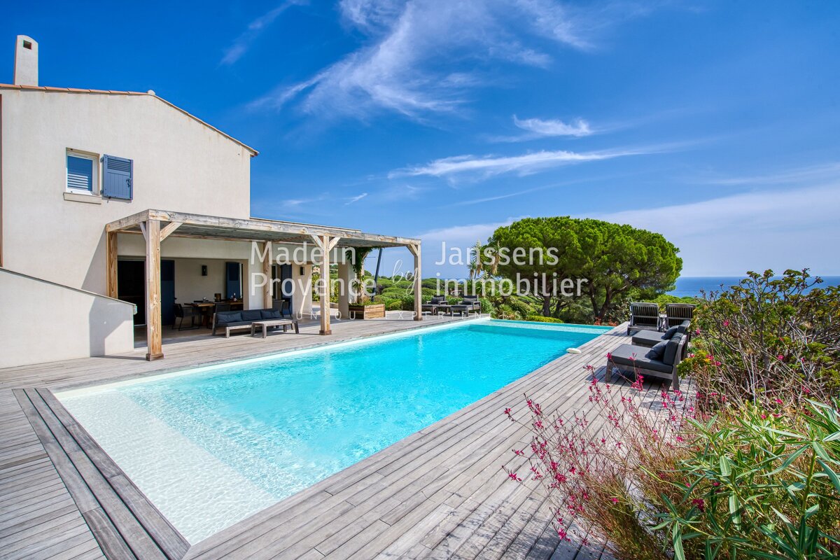 A large swimming pool in front of a house that says janssens immobilier