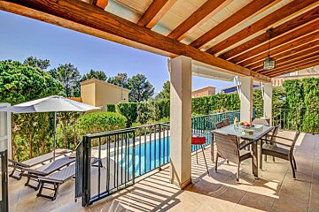 A patio with a table and chairs overlooking a pool