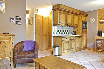 A kitchen with wooden cabinets and a clock on the wall