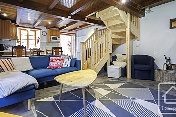 A living room with a blue couch and a wooden staircase