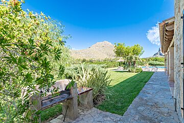 A lush green yard with a bbq and a mountain in the background