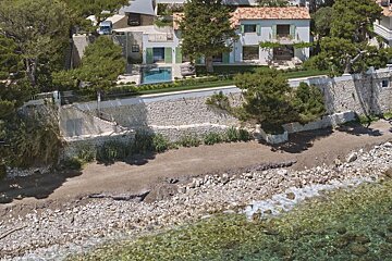 An aerial view of a house on a cliff overlooking the ocean
