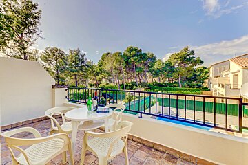 A table and chairs on a balcony overlooking a pool
