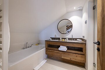 A bathroom with two sinks and a round mirror