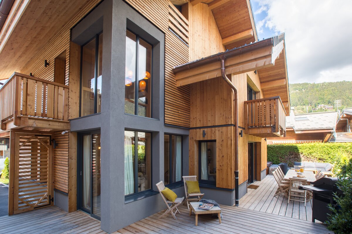 The outside of a house with a wooden deck and chairs