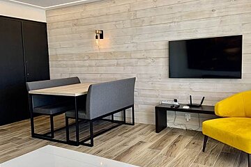 A living room with a table and chairs and a flat screen tv