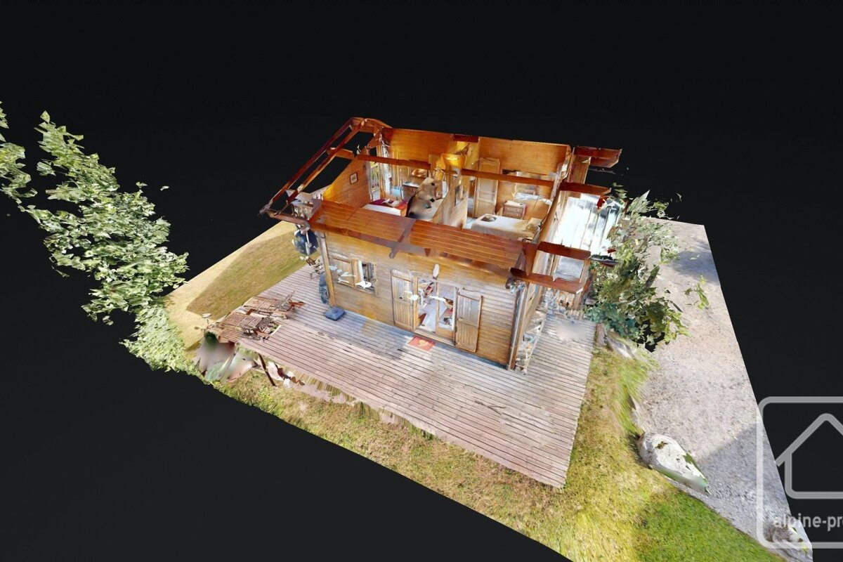 A 3D scan of a wooden chalet, top removed to show interior layout. Features a large deck, grassy surroundings, and trees against a dark background.
