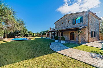 A large stone house with a swimming pool in front of it