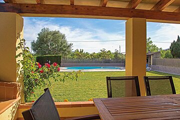 A patio with a table and chairs overlooking a swimming pool