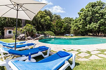 A swimming pool with blue lounge chairs and a white umbrella