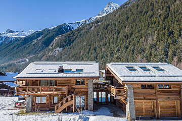 A snowy mountain behind a house with a balcony