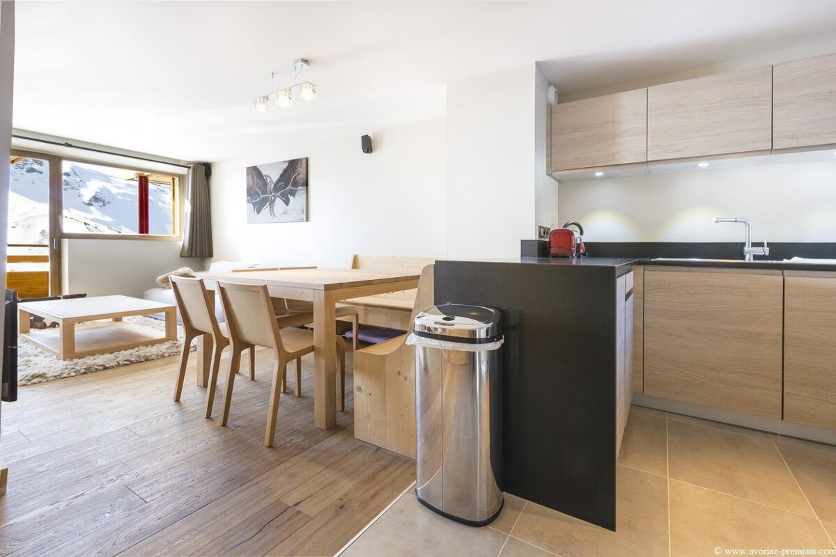 A kitchen with a table and chairs and a trash can