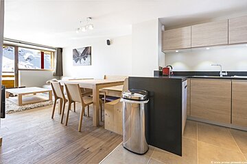 A kitchen with a table and chairs and a trash can