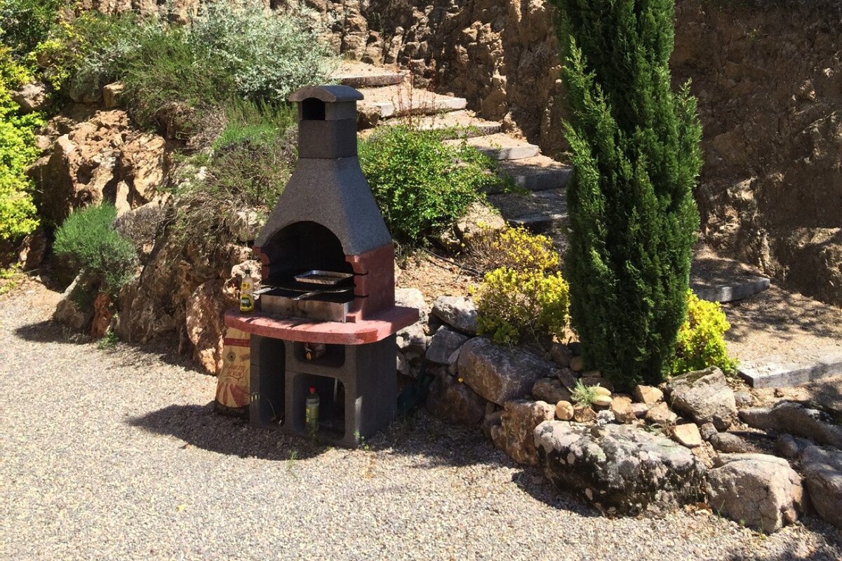 A bottle of olive oil sits next to a grill