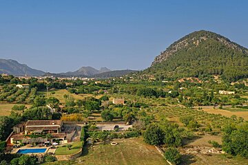 An aerial view of a lush green valley with mountains in the background