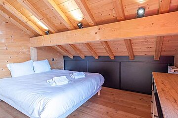 A bedroom with a wooden ceiling and a bed