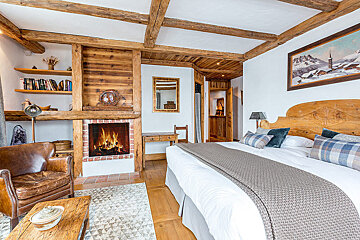 A bedroom with a large bed and a fireplace