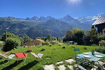 A lawn with chairs and a table with mountains in the background