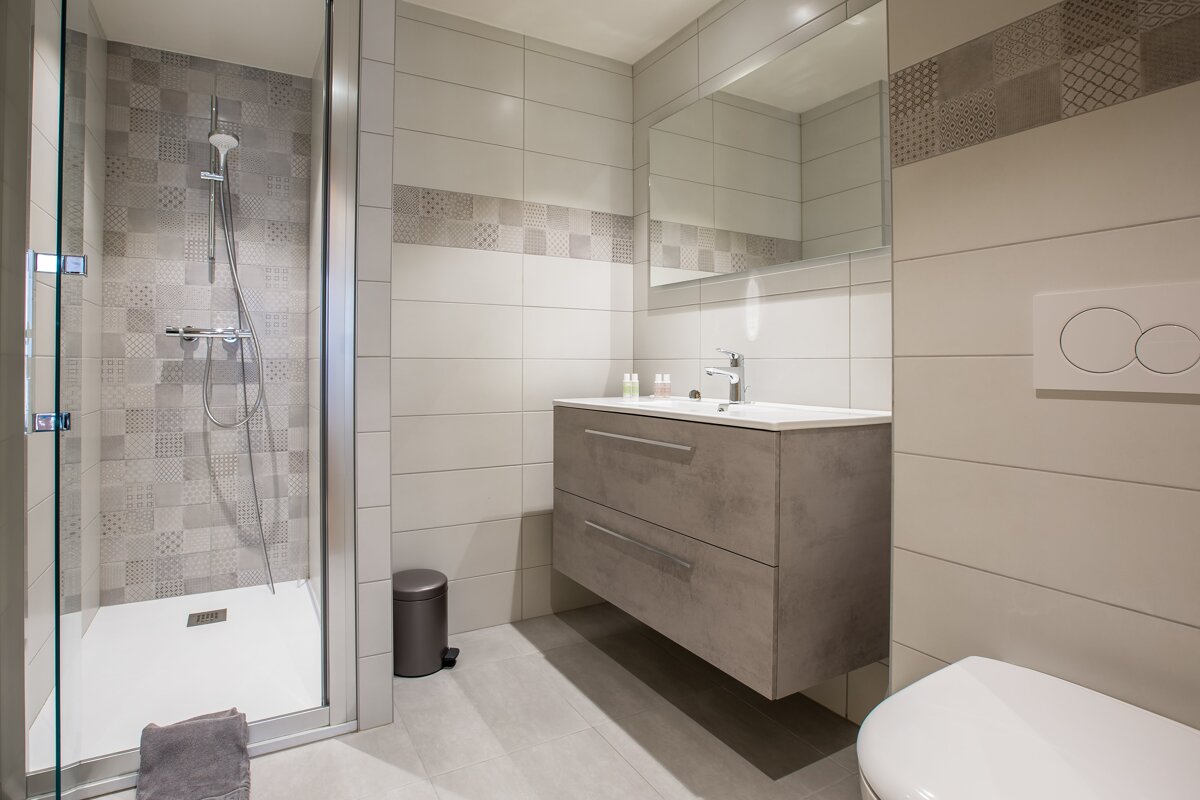 A bathroom with a walk in shower and a sink