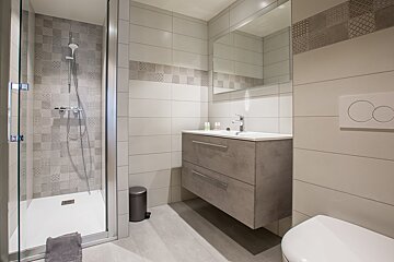 A bathroom with a walk in shower and a sink