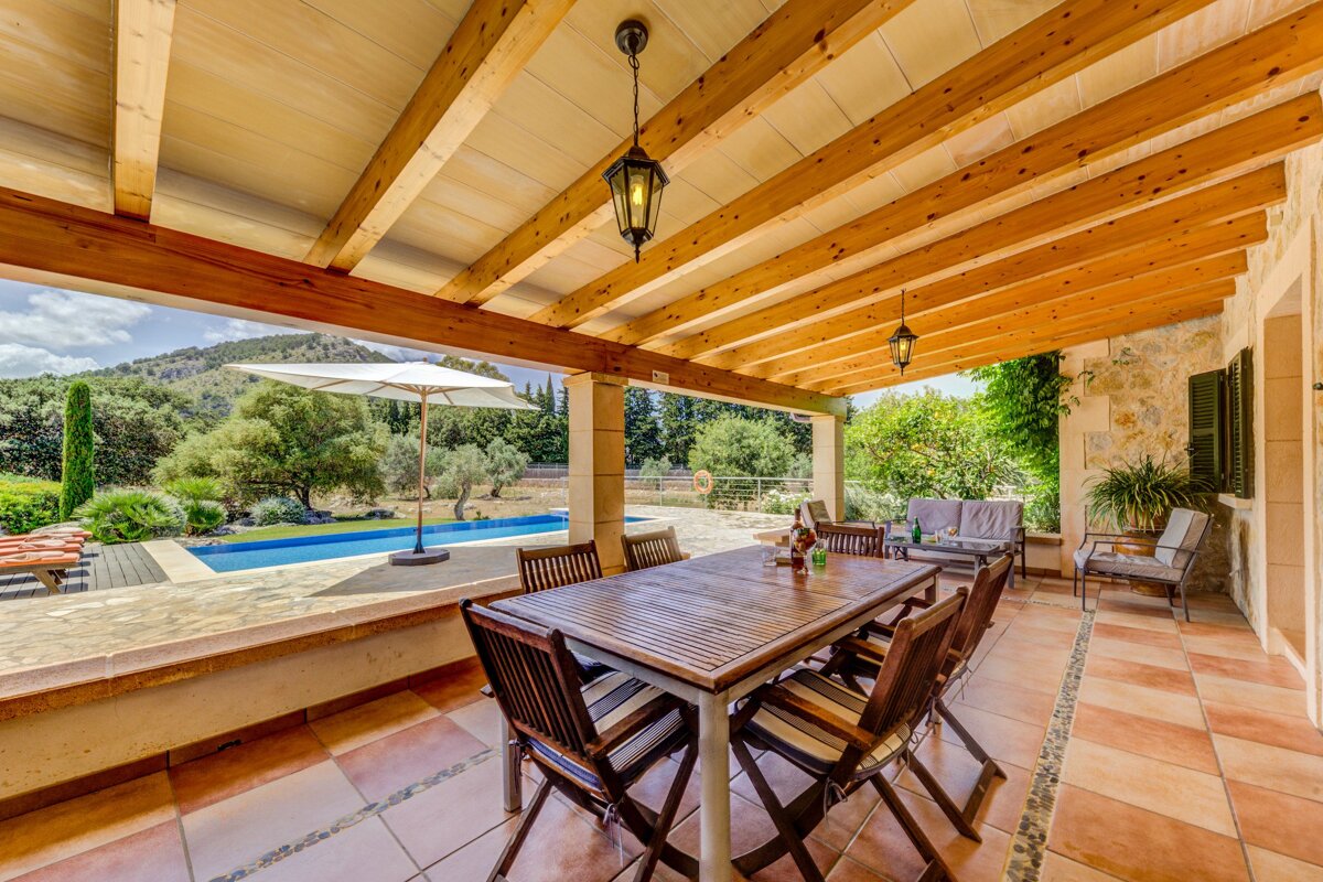 A patio with a table and chairs under a wooden roof