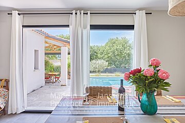 A bottle of wine sits on a table in front of a window that says made in provence immobilier
