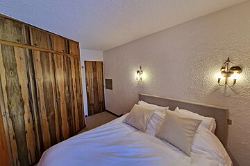 A bedroom with a bed and wooden cabinets
