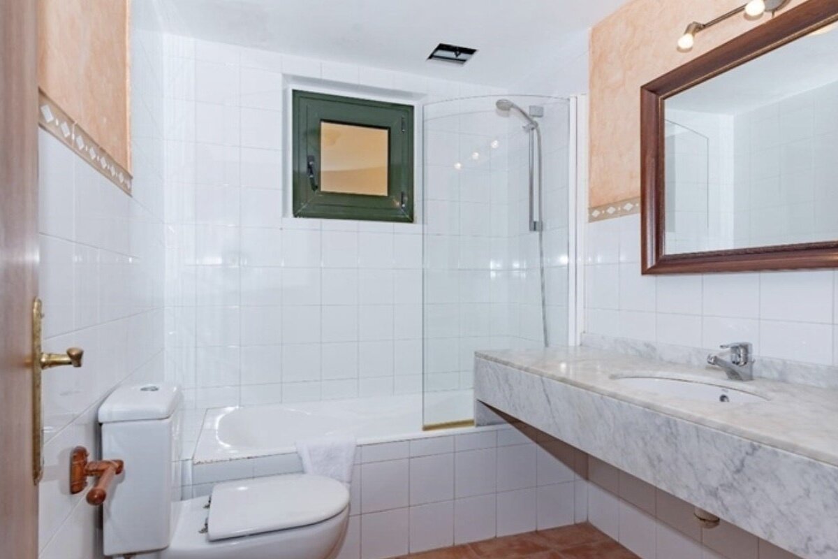 A bathroom with a toilet a sink and a window