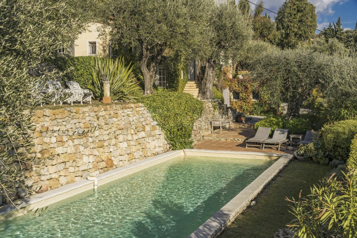 A stone wall surrounds a large swimming pool