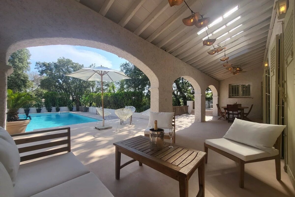 A luxurious patio with a swimming pool, lounge seating, and an arched stone ceiling.