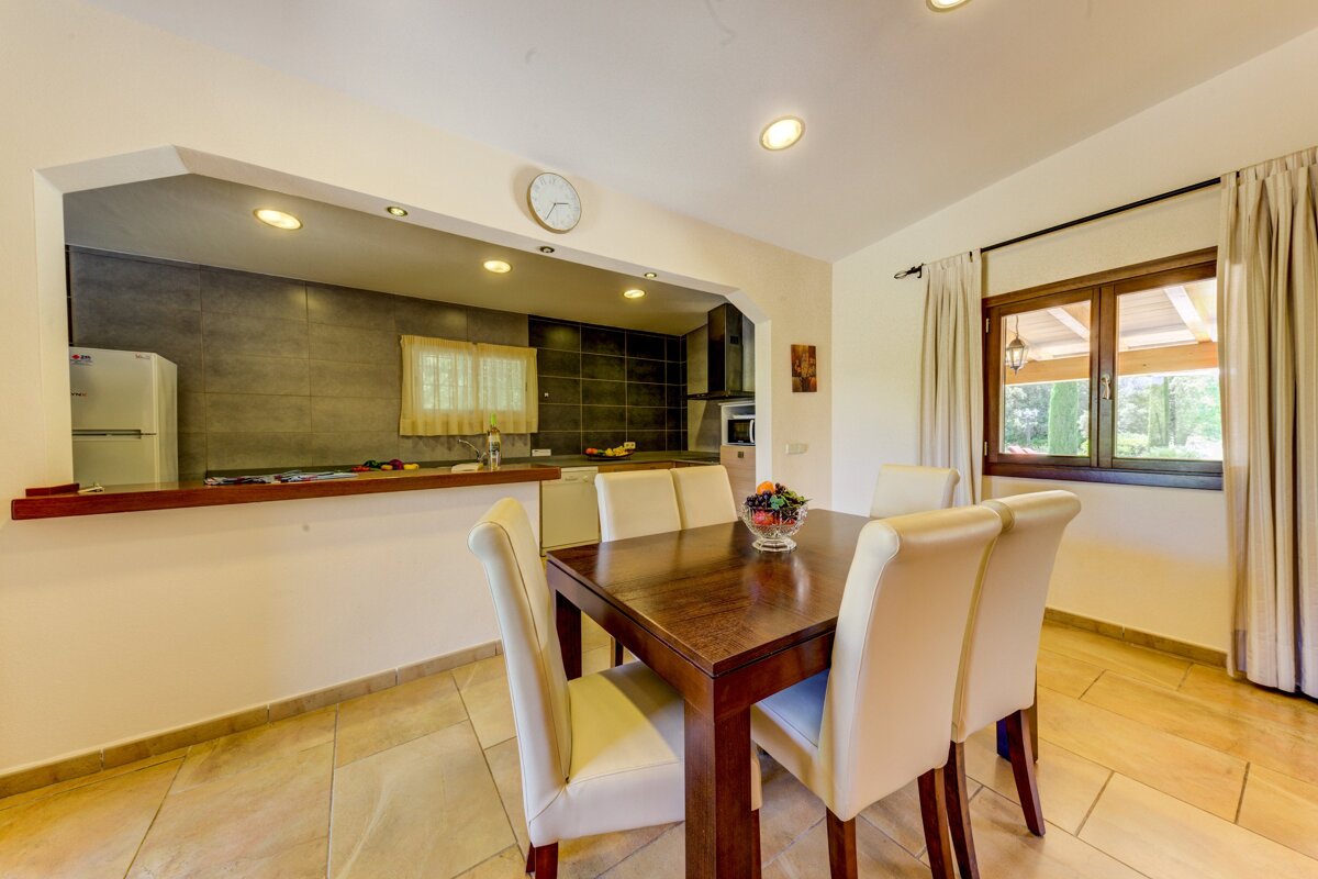 A kitchen with a table and chairs and a clock on the wall
