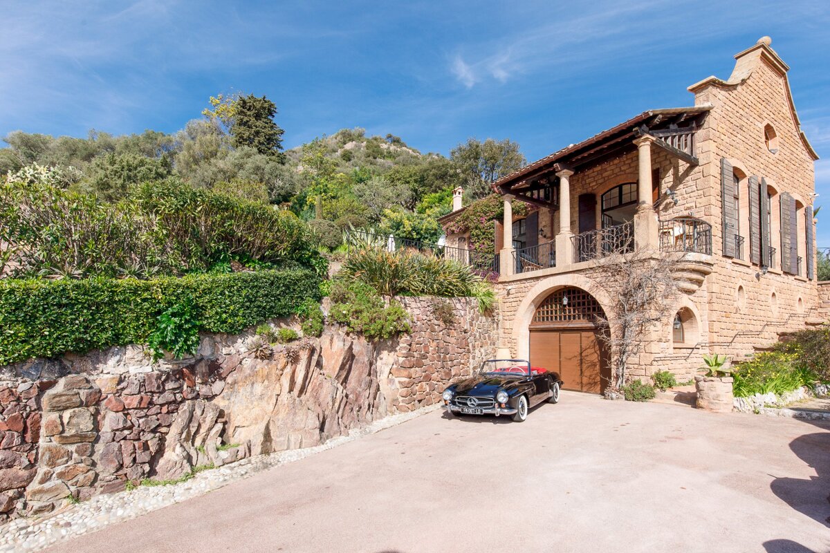 A black car is parked in front of a stone building