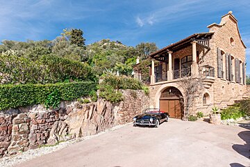 A black car is parked in front of a stone building