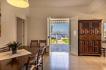 A dining room with a table and chairs and an open door