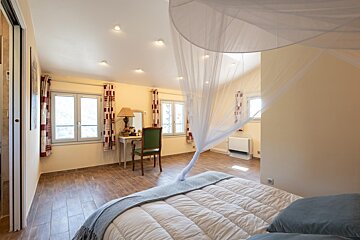 A bedroom with a canopy bed and a desk