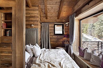A wooden bedroom with a bed and a window