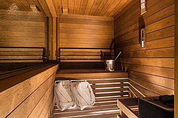 A wooden sauna with a bucket on the bench