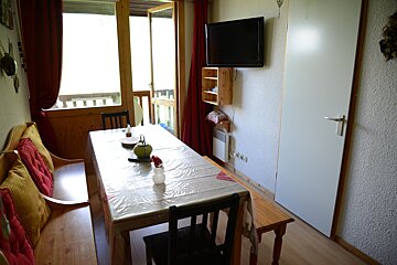 A dining room with a table and chairs and a flat screen tv