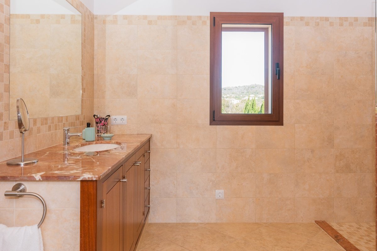 A bathroom with a sink and a mirror and a window